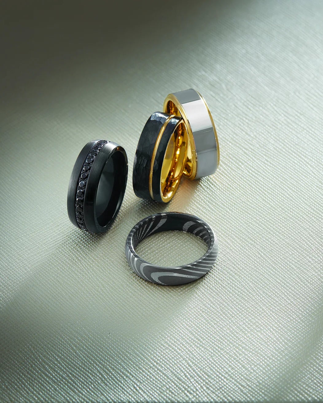 Set of five rings with different designs on a textured surface